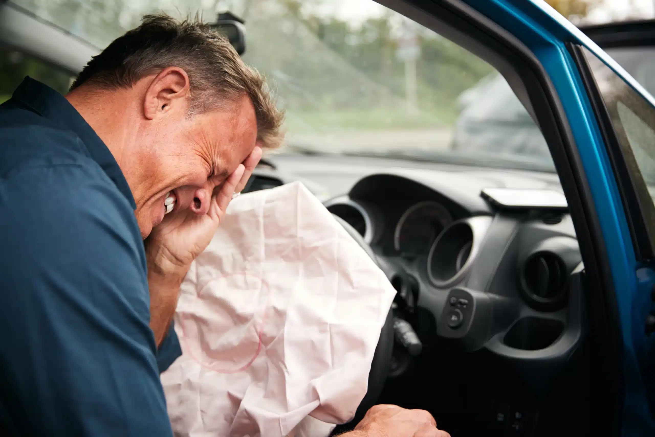 When Minor Car Accidents Lead to Major Injuries: What Illinois Drivers Need to Know 1 Injured man in a car clutching his forehead in pain, with a deployed airbag after an accident.