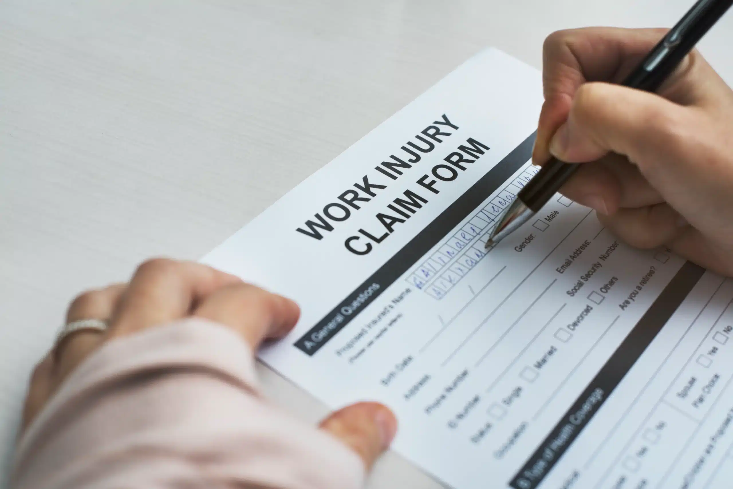 Close-up of a 'Work Injury Claim Form' being filled out, symbolizing the importance of legal assistance when Illinois workers' compensation claims are denied.