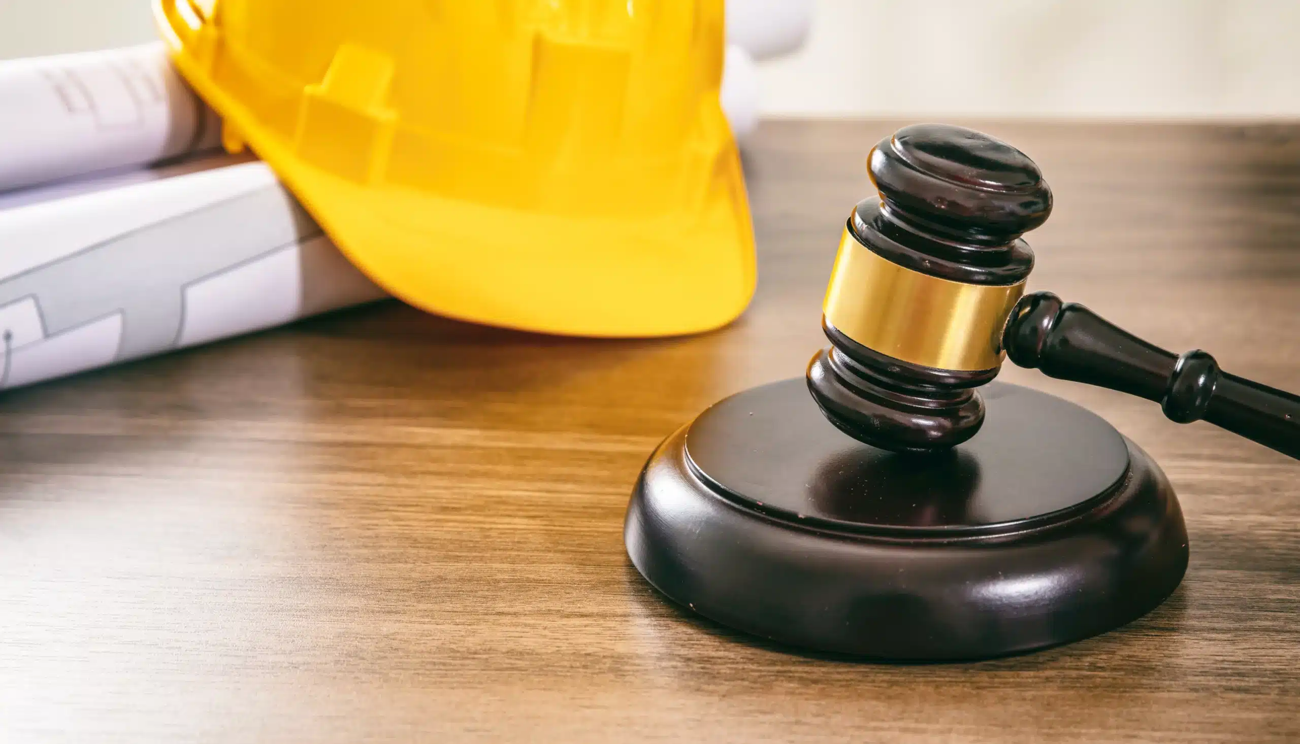 Construction helmet, gavel, and blueprints on desk, symbolizing legal considerations in Chicago workers' compensation settlements.